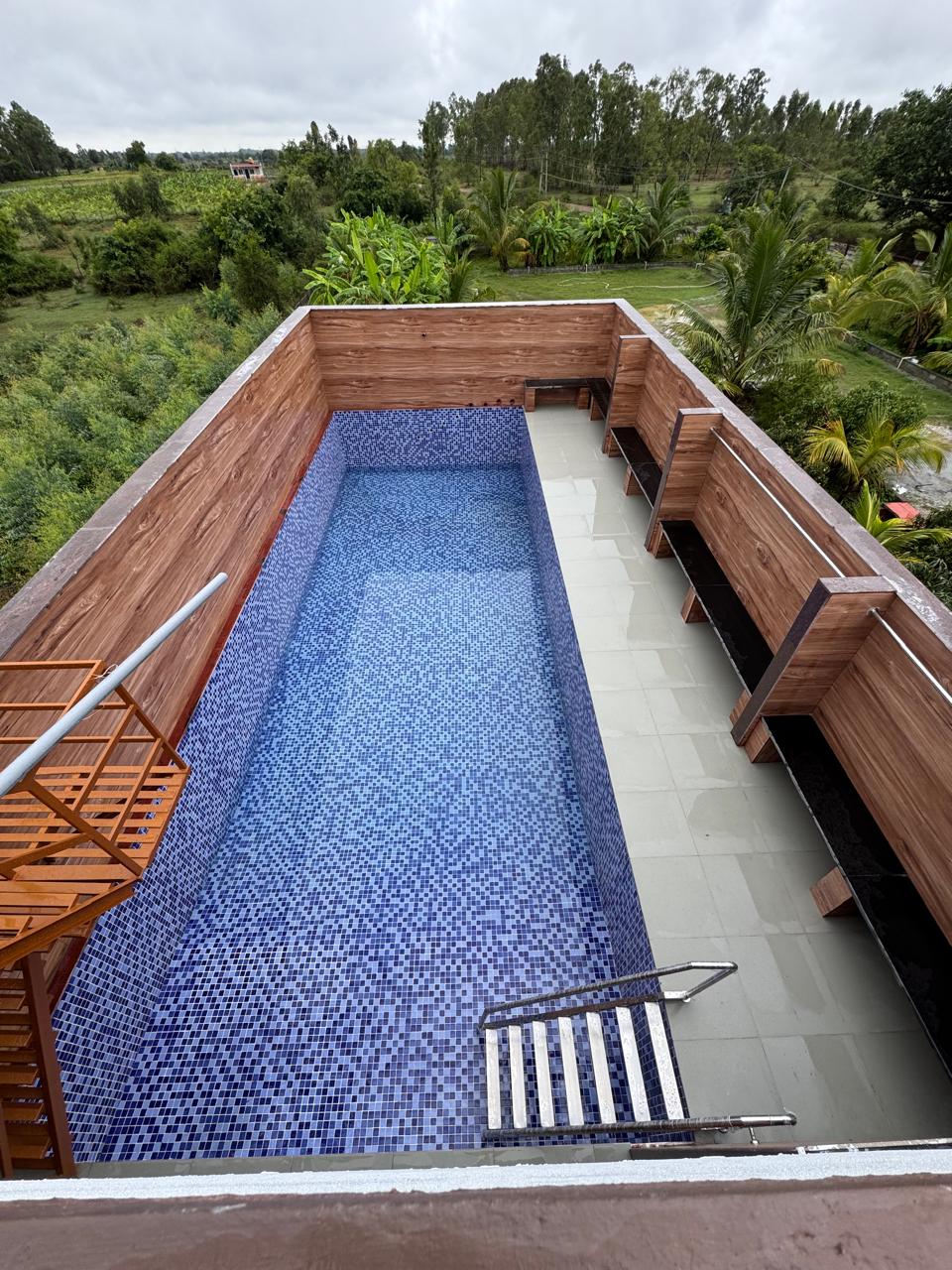 Rooftop swimming pool with blue mosaic tile finish and wooden deck